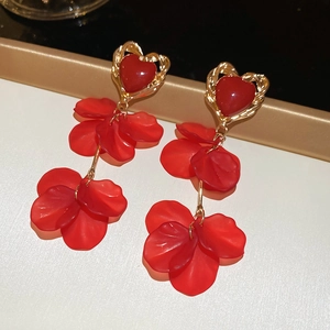 Detail view of heart-shaped gold frame with red petals dangling on display stand