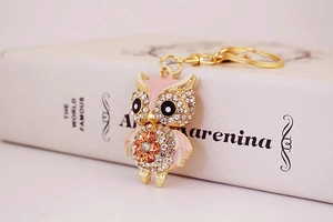 Detailed view of pink owl keychain with sparkling crystals leaning against a book