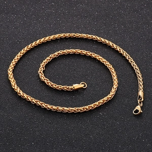 Close-up of golden wheat chain necklace with sturdy lobster clasp on dark background