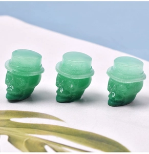 Detailed view of three green translucent skull charms with top hats for DIY jewelry