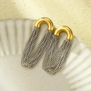 Detail of gold arch stud earrings with flowing silver metal chain tassels on ceramic