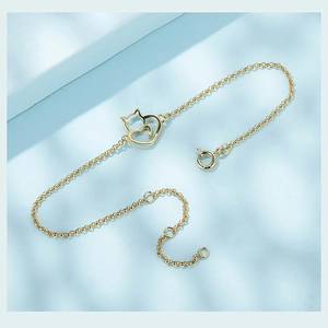Dettaglio dei ciondoli a forma di gatto e cuore dorati su un bracciale in argento S925