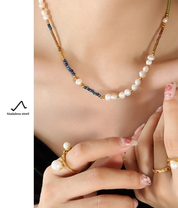 Detail of freshwater pearl necklace and stainless steel gold rings set on model