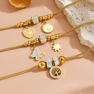 Gros plan détaillé de bracelets serpent dorés avec pendentifs cœur, papillon et arbre de vie