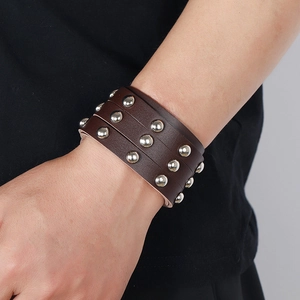 Close-up of a wide dark brown leather punk bracelet with rows of silver metal studs