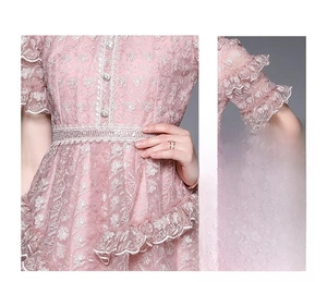 Détails de broderies florales et manches à volants sur robe en dentelle rose