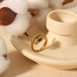 Vintage 18k gold plated snake ring with green zircon eyes on a minimalist display