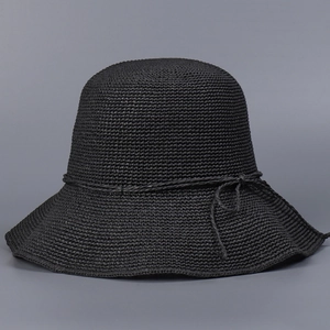 Close-up of black handmade crochet straw sun hat featuring a delicate bow tie detail