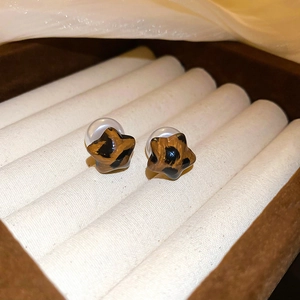 Macro shot of brown leopard print star-shaped earrings in a cream jewelry box