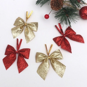 Close-up of sparkling red and gold glitter Christmas bows with festive pine cone accents