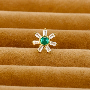 Macro view of a gold flower stud earring with green center gem and white zircon petals