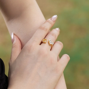 Detail of adjustable gold ring with twin heart-shaped zircons on woman's hand