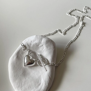 Detail of 925 sterling silver heart necklace with a toggle clasp on a white stone