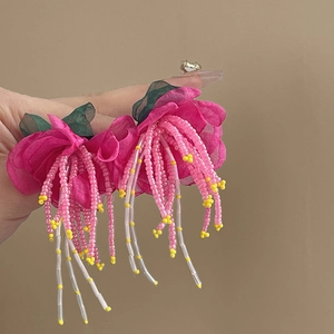 Close-up of pink fabric floral tassel earrings with beaded strands in bohemian style