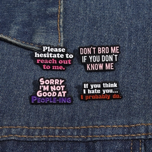 Detail of four enamel pins with funny slogans pinned on blue denim fabric texture