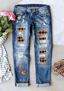 Gros plan d'un jean déchiré avec des patchs à carreaux orange et des motifs de feuilles