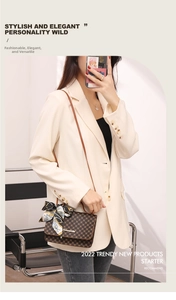 Detailed view of brown monogram crossbody bag with silk scarf handle on casual suit