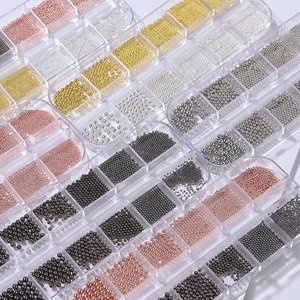 Mixed metal nail art beads in gold and silver colors stored in a multi-grid plastic box