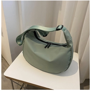 Detail view of water-resistant green oxford crescent bag with dual zippers and strap