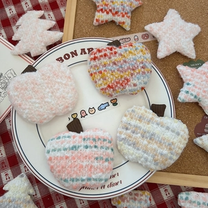 Macro shot of knitted Christmas ornaments like stars and trees on a ceramic plate