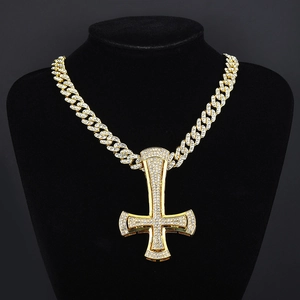 Macro shot of hip hop inverted cross pendant with iced-out crystals on a gold cuban chain