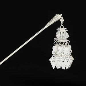 Detailed close-up of intricate silver filigree pendant on a traditional tassel hair pin
