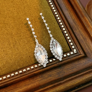 Detail of silver drop earrings with marquise-cut crystals on a brown velvet background