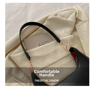 Detail view of black leather half-moon bag with gold buckle and red patterned lining