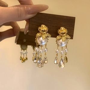 Détail de boucles d'oreilles rose vintage avec perle blanche et gouttes en cristal