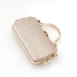 Detail of gold evening clutch bag featuring glitter fabric and hanging pearl tassels