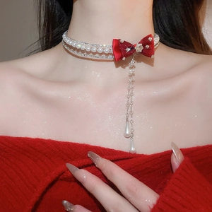 Detail of three-layer pearl choker with red velvet bow and dangling rhinestone tassels