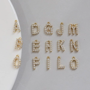 Macro detail of gold-plated A-O alphabet charms with cubic zirconia for DIY jewelry