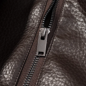 Detail shot of the metallic zipper and lychee grain texture on dark brown PU leather