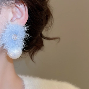 Detailed close-up of sky blue faux fur earrings with zircon accents and large white pearls