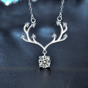 Macro shot of silver deer antler pendant with sparkling moissanite stone on dark base