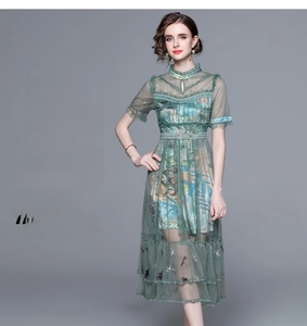 Detail of the high-waisted floral embroidery and tiered mesh hem on a green midi dress