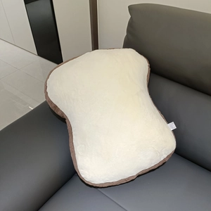 Close-up of soft cartoon toast plush pillow with plush texture on a leather sofa