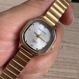 Close-up of gold octagon women's watch featuring a diamond-set dial on wooden background