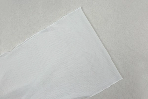 Detail von weißem, transparentem Strickstoff zeigt die Textur eines asymmetrischen Kleids