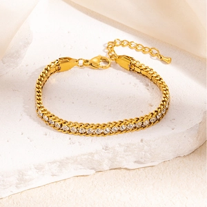 Close-up of golden Cuban link bracelet with sparkling cubic zirconia on stone background