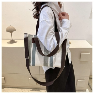 Detailed view of striped canvas tote bag worn by a model in a minimalist home setting
