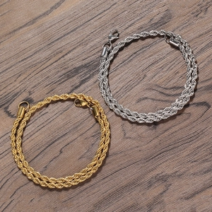 Detail of 5mm gold and silver rope chains with lobster clasps on a wood surface