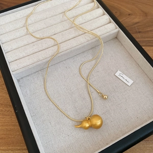 Dettaglio del pendente a zucca in oro spazzolato e catena a serpente su vassoio portagioie