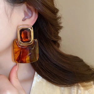 Close-up of amber resin earrings with gold metal frame worn by a model in profile