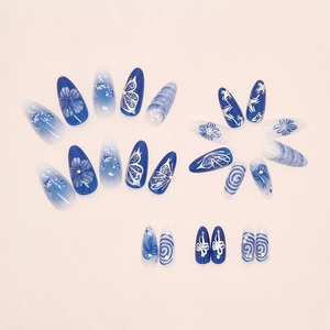 Detail of blue and white almond press-on nails with 3D pearls and butterfly patterns