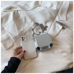 Mini silver octagonal acrylic evening bag with chain strap compared to a smartphone