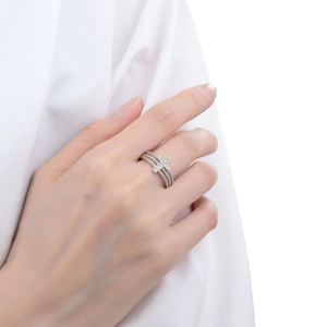Close-up of layered silver ring with zircon cross design worn on a finger