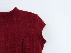 Gros plan sur l'épaule d'une robe en tweed rouge avec texture tissée et encolure élégante