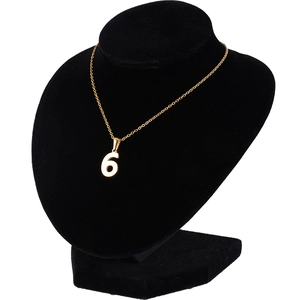 Détail du pendentif chiffre 6 en acier inoxydable doré sur un support de buste noir