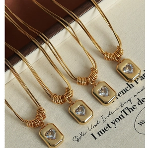 Macro detail of vintage gold snake chains with heart-shaped zircon pendants